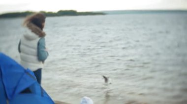 Mutlu ve güzel anne ve kızı nehir kıyısında plaj üzerinde martı besleniyor