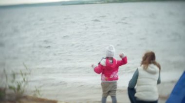 Mutlu ve güzel anne ve kızı nehir kıyısında plaj üzerinde martı besleniyor