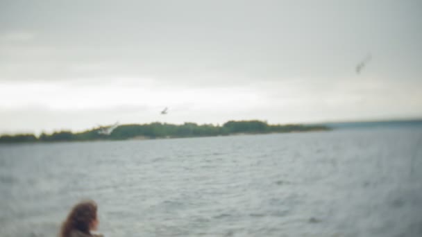 Szczęśliwe i piękne matka i córka są karmienia mewy na plaży, nad brzegiem rzeki — Wideo stockowe