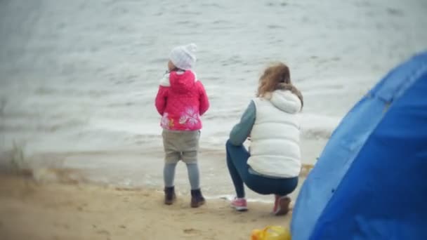 Feliz y hermosa madre e hija están alimentando gaviotas en la playa en la orilla del río — Vídeos de Stock