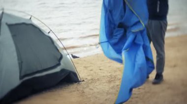Adam bir turist çadır nehir deniz kıyısında toplar.