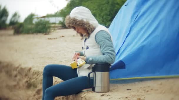 Krásná dívka s její rodinou hraje na ukulele na břehu řeky poblíž turistické stany — Stock video