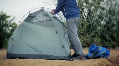 Adam bir turist çadır nehir deniz kıyısında toplar.