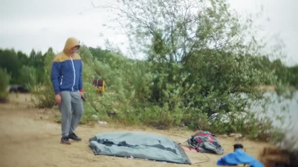 Человек собирает туристическую палатку на берегу реки моря — стоковое видео
