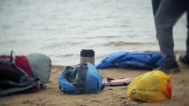 Člověk shromažďuje turistický stan na břehu řeky u moře — Stock video