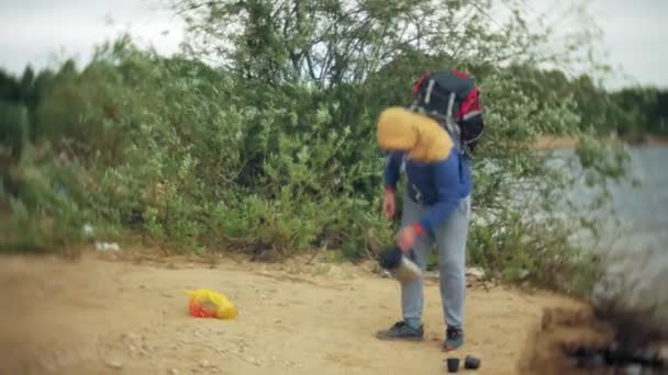 L'homme recueille une tente touristique sur la rive de la rivière de la mer — Video