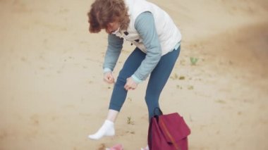 Bir kadın kum sahilde deniz kenarında, hayattan zevk yürüyor