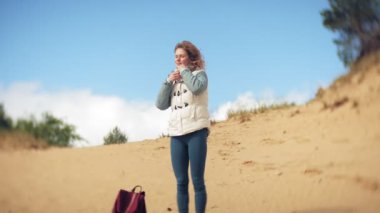 Bir kadın kum sahilde deniz kenarında, hayattan zevk yürüyor