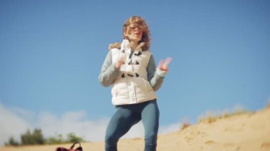 Bir kadın kum sahilde deniz kenarında, hayattan zevk yürüyor