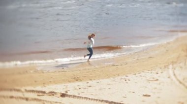 Bir kadın kum sahilde deniz kenarında, hayattan zevk yürüyor