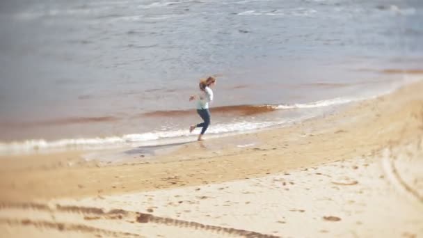 Una mujer está caminando por la arena en la playa junto al mar, disfrutando de la vida — Vídeo de stock