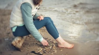 Bir kadın kum sahilde deniz kenarında, hayattan zevk yürüyor