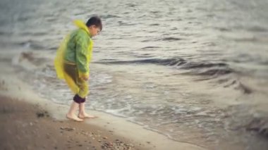 Bir çocuk denize yakın sahilde yürüyor