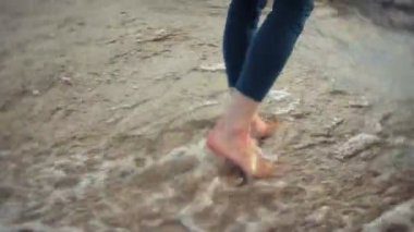 Bir kadın kum sahilde deniz kenarında, hayattan zevk yürüyor