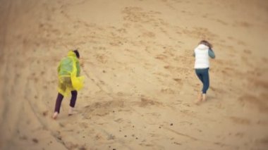 Anne oğlunu yağmurluk ile çalış ve sahilde deniz aşağı çalışır