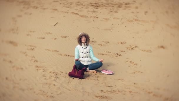 Mujer sentada en una pose de loto yoga sobre la arena cerca del agua — Vídeo de stock