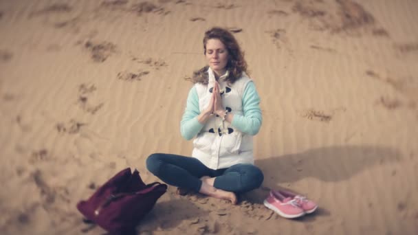 ロータス ヨガのポーズ、水の近くの砂の上に座っている女性 — ストック動画