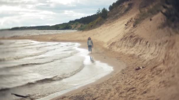 Una mujer está caminando por la arena en la playa junto al mar, disfrutando de la vida — Vídeo de stock