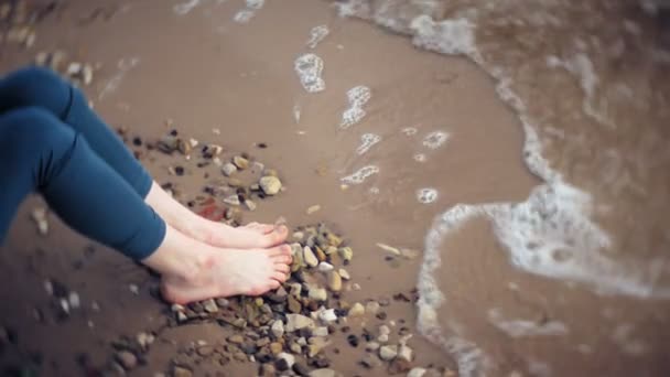 Uma mulher está caminhando ao longo da areia na praia junto ao mar, desfrutando da vida — Vídeo de Stock