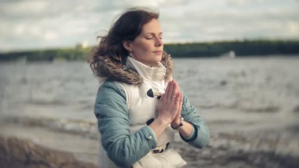 Femme assise dans une pose de yoga lotus sur le sable près de l'eau — Video