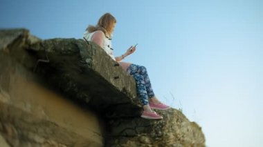 Genç bir kadın eski bir bağbozumu Demiryolu Köprüsü yakınlarında bir akıllı telefon kullanıyor. 4k