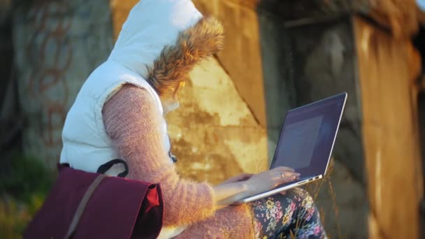 Jonge vrouw die op laptop in de buurt van oude vintage spoorbrug werkt. — Stockvideo