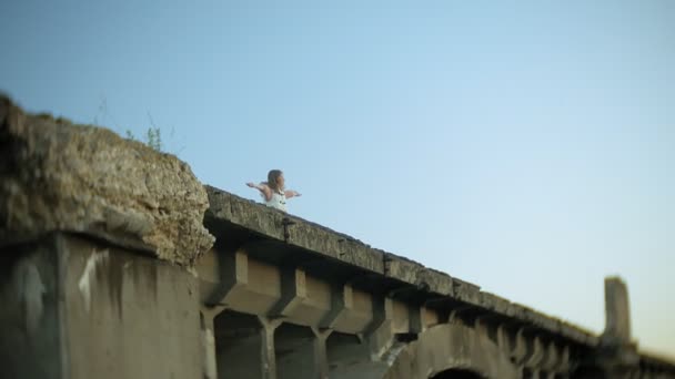 Jonge vrouw loopt in de buurt van de oude vintage spoorbrug. — Stockvideo