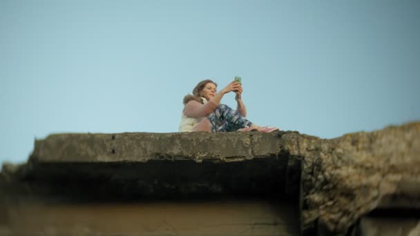 Eine junge Frau benutzt ein Smartphone in der Nähe einer alten Eisenbahnbrücke. — Stockvideo