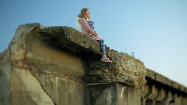 A young woman is using a smartphone near an old vintage railway bridge. — Stock Video