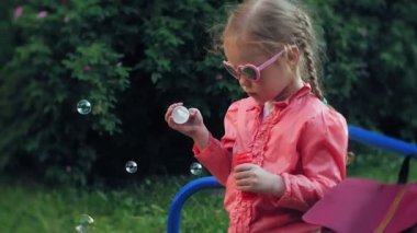 Sabun köpüğü bahar parkta üfleyen mutlu çocuk.