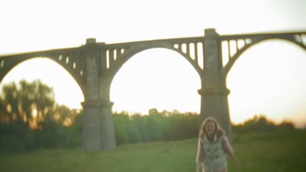 Ung kvinna går nära gamla vintage järnvägsbron. — Stockvideo