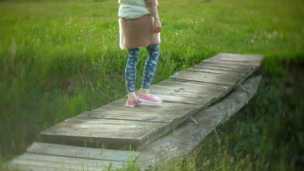 Jonge vrouw loopt in de buurt van de oude vintage spoorbrug. — Stockvideo