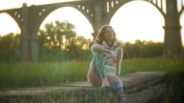 Jonge vrouw loopt in de buurt van de oude vintage spoorbrug. — Stockvideo