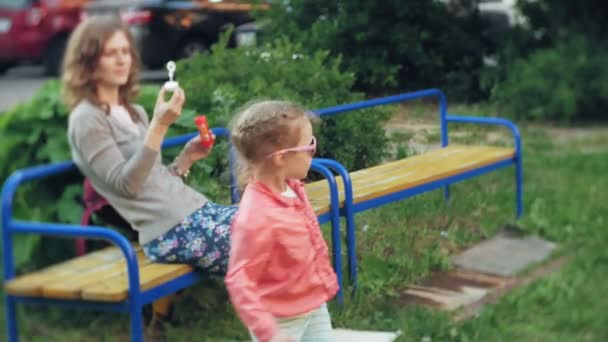 幸せな母と彼女の小さな娘が屋外、吹くシャボン玉を一緒に遊んで、裏庭に楽しい時を過します。自然。美ママと一緒に公園で彼女の子供。ママと赤ちゃん — ストック動画