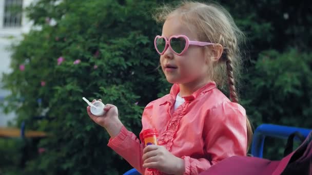 Glückliches Kind pustet Seifenblasen im Frühlingspark. — Stockvideo