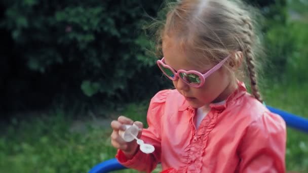 Šťastné dítě fouká mýdlové bubliny v parku na jaře. — Stock video