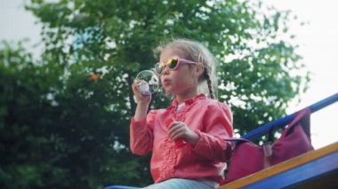 Sabun köpüğü bahar parkta üfleyen mutlu çocuk.