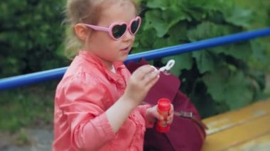 Sabun köpüğü bahar parkta üfleyen mutlu çocuk.