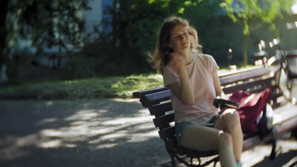 Женщина катается на роликах и слушает музыку на наушниках по телефону в парке — стоковое видео