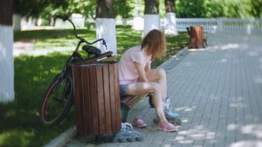 Tekerlekli paten parkta bankta oturan kadın Giydir