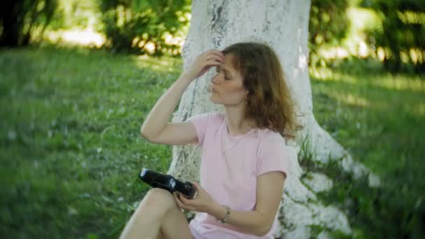 Mujer patinando y escuchando música en los auriculares en el teléfono en el parque — Vídeos de Stock
