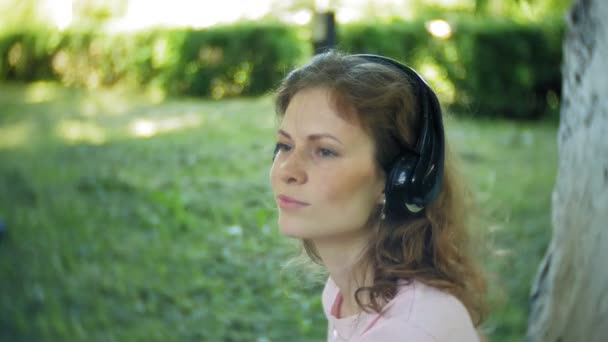 Kobieta rolkach i słuchanie muzyki na słuchawkach przez telefon w parku — Wideo stockowe