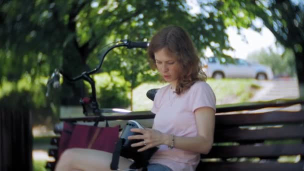 Jonge vrouw maakt gebruik van hoofd gemonteerde display in het park. Spelen spel met behulp van Vr-helm voor slimme telefoons. Gelukkig — Stockvideo