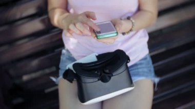 Genç kadın parkta başa takılı ekran kullanır. Akıllı telefonlar için VR-kask kullanarak oyun oyun. Mutlu