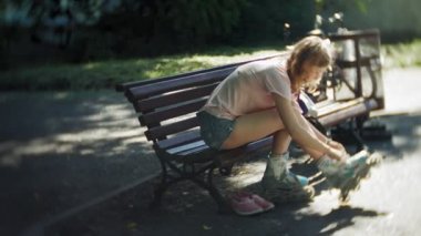 Tekerlekli paten parkta bankta oturan kadın Giydir
