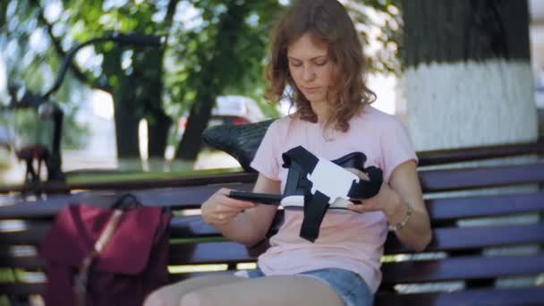 Mujer joven utiliza la pantalla montada en la cabeza en el parque. Jugar a juego con casco VR para teléfonos inteligentes. Feliz. — Vídeo de stock