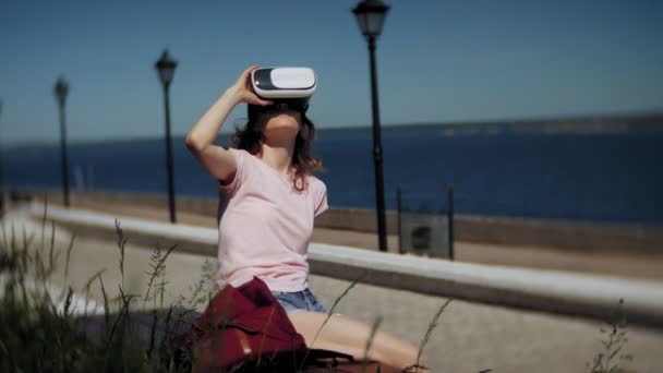 Genç kadın parkta başa takılı ekran kullanır. Akıllı telefonlar için VR-kask kullanarak oyun oyun. Mutlu — Stok video