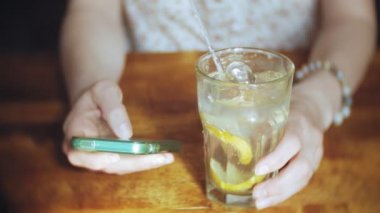 bir kadın bir restoranda bir kokteyl içer ve telefon kullanır