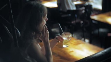 bir kadın bir restoranda bir kokteyl içer ve telefon kullanır