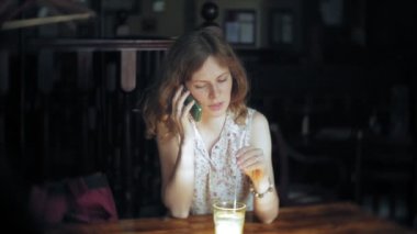 bir kadın bir restoranda bir kokteyl içer ve telefon kullanır